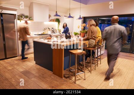 Motion Blur Shot Of Mature Friends Meeting At Home For Evening Dinner Party Stock Photo