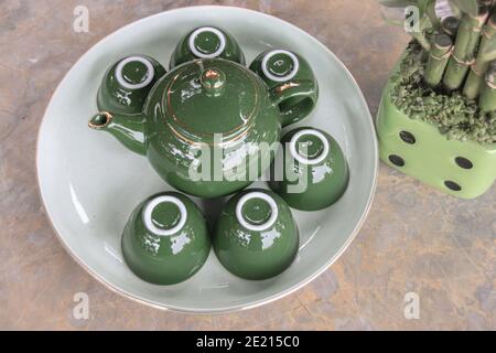 Closeup of a traditional, green ceramic tea set on a white plate Stock Photo