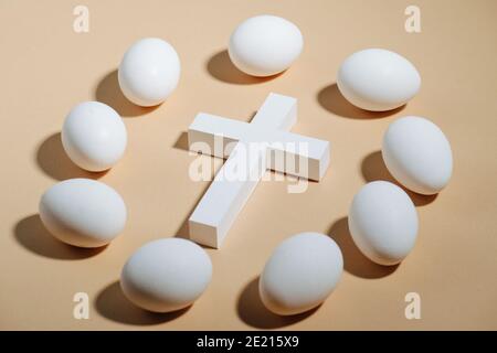 Christian cross surrounded by white eggs on beige background Stock Photo