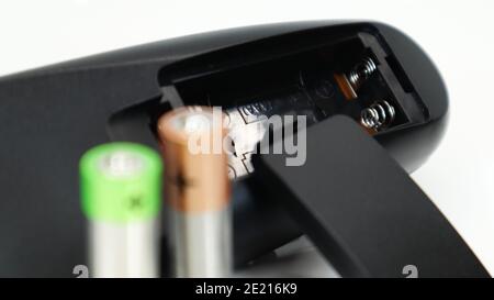 Black TV remote control with AAA alkaline batteries on a white background. Battery replacement, spare parts. Close up of an empty battery compartment Stock Photo