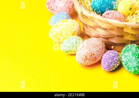 Happy easter. Pastel eggs in basket on yellow background flatlay with space for text.  Stock Photo