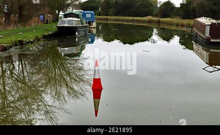 After a spell of freezing cold weather the water’s of the canal had frozen over and someone has positioned a traffic cone on the ice. Stock Photo