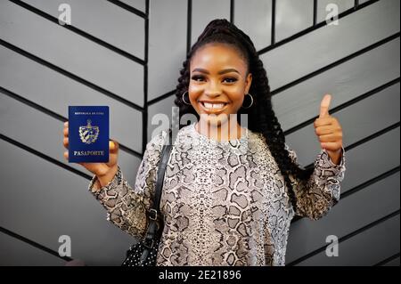 Close up portrait of young positive african american woman holding Cuba passport and thumbs up. Stock Photo