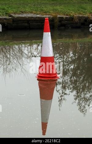 Cone on the ice, after a spell of freezing cold weather the water’s of the canal had frozen over and someone has positioned a traffic cone on the ice. Stock Photo