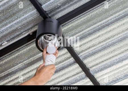 Hand holding LED bulb to replace fluorescent lamp, concept for energy saving and environmental protection. Stock Photo