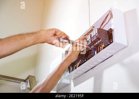 Close up of hand using a screwdriver to tighten the circuit breaker to prevent power supply to the control box. Stock Photo