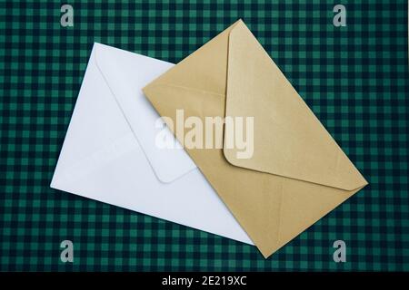White and beige envelopes and on a green checkered background. Blank template Stock Photo