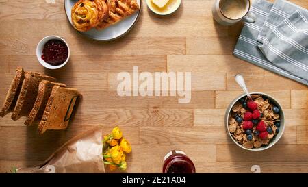 Overhead Flat Lay Shot Of Table Laid For Breakfast With Toast Cereal Croissant Pastries And Flowers Stock Photo