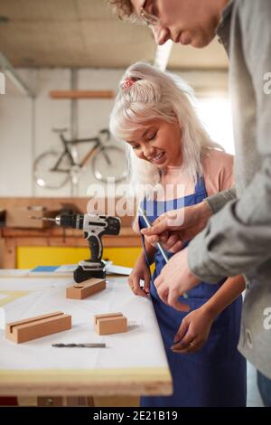 Craftsman Mentoring Female Apprentice In Workshop Building Sustainable Bamboo Bicycles Stock Photo