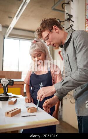 Craftsman Mentoring Female Apprentice In Workshop Building Sustainable Bamboo Bicycles Stock Photo