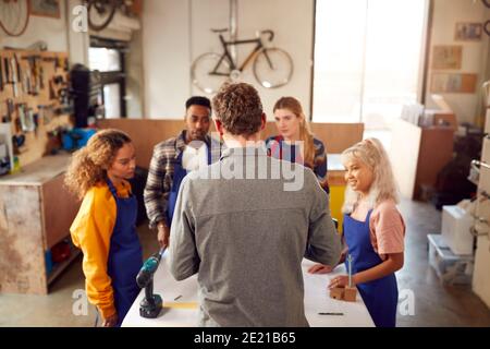 Multi-Cultural Team In Workshop Assembling Hand Built Sustainable Bamboo Bicycle Frame Stock Photo