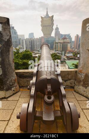 Macau, China.  Cannon on Forteleza do Monte, or Mount Fortress.  Grand Lisboa Hotel in background.  The fort is part of the Historic Centre of Macau, Stock Photo