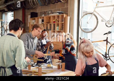 Multi-Cultural Team In Workshop Assembling Hand Built Sustainable Bamboo Bicycle Frame Stock Photo