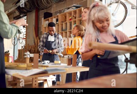Multi-Cultural Team In Workshop Assembling Hand Built Sustainable Bamboo Bicycle Frame Stock Photo
