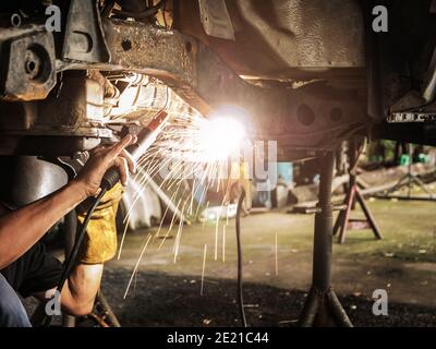 Technician are welding assembly steel under the car in automotive industrial factory -Automotive industry and garage concepts. Stock Photo