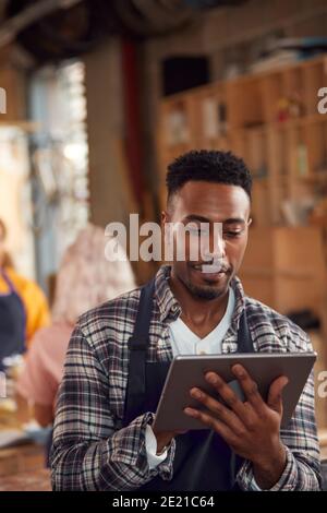 Male Craftsman In Carpentry Workshop For Bamboo Bicycles Using Digital Tablet Stock Photo