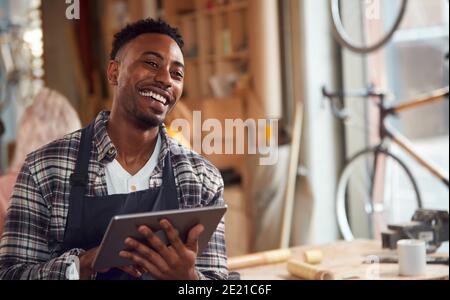 Male Craftsman In Carpentry Workshop For Bamboo Bicycles Using Digital Tablet Stock Photo