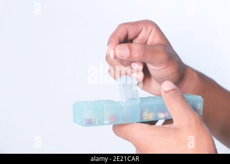 man's hands taking medicine from a pill box isolated on white  Stock Photo
