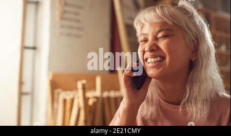 Female Business Owner In Workshop Making Call On Mobile Phone Stock Photo