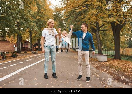 Two gay parents with their adopted daughter walking in park together. Happy LGBT family concept. Stock Photo