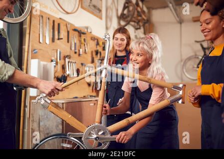 Multi-Cultural Team In Workshop Assembling Hand Built Sustainable Bamboo Bicycle Frame Stock Photo