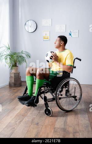 disabled african american sportsman in wheelchair holding football Stock Photo