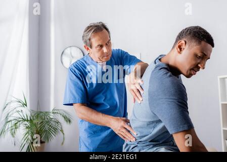 mature chiropractor working with young african american man Stock Photo