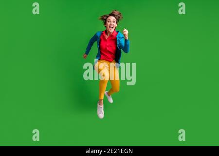 Full length body size photo of jumping high running fast happy girl isolated on vibrant green color background Stock Photo