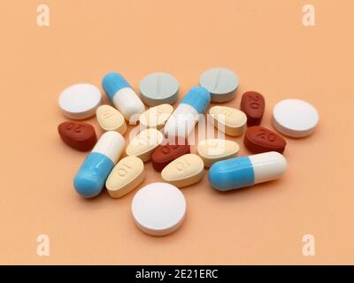 Stockholm, Sweden - January 10, 2021: A pile of different colored pills on an orange background. Perhaps illustrating the overprescription of drugs in Stock Photo