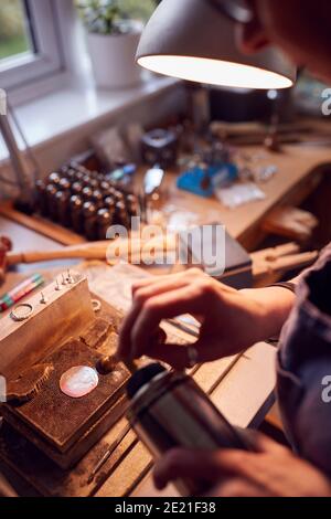 Close Up Of Male Jeweller Working On Brooch With Blowtorch In Studio Stock Photo