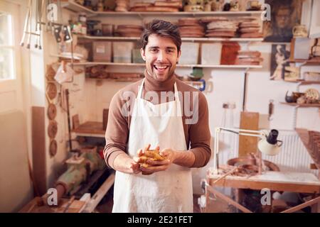 Portrait Of Male Potter Cleaning Hands With Sponge In Ceramics Studio Stock Photo