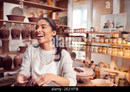 Female Potter Fitting Clay Handles To Mugs In Ceramics Studio Stock Photo