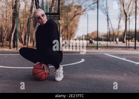 Attractive young woman wearing glasses and holding a basketball while playing outdoors Stock Photo