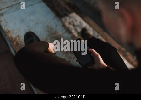 Top view of lady hands using smartphone while sitting metal construction outdoors Stock Photo