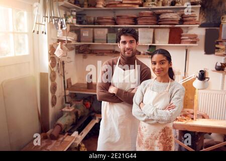 Portrait Of Couple Running Bespoke Pottery Business Working In Ceramics Studio Together Stock Photo