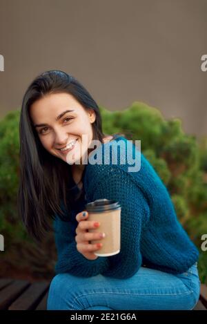 Attractive smiling female with long dark hair spending leisure time outdoors in calm peaceful square and enjoying her loneliness Stock Photo