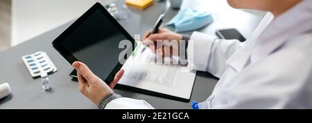 Unrecognizable female doctor using tablet while working Stock Photo