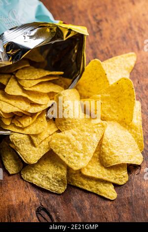 Salted tortilla chips. Yellow nachos triangle on wooden table. Stock Photo