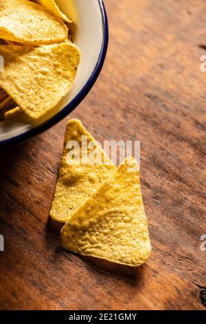Salted tortilla chips. Yellow nachos triangle on wooden table. Stock Photo