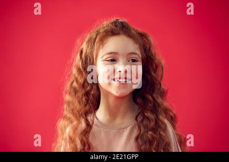 Portrait Of Girl With Long Red Hair Against Red Studio Background Smiling At Camera Stock Photo