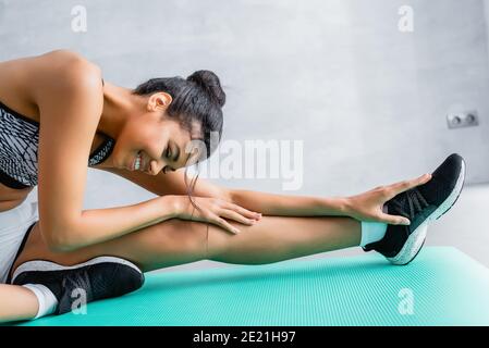 smiling african american sportswoman stretching on fitness mat at home Stock Photo