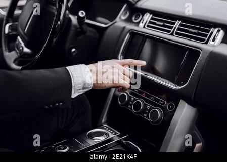 Cropped photo of businessman changing stations on his automobile radio. Transportation and vehicle concept Stock Photo