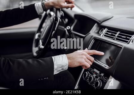 Close up of man driving car with audio stereo system on board computer. Transportation and vehicle concept Stock Photo