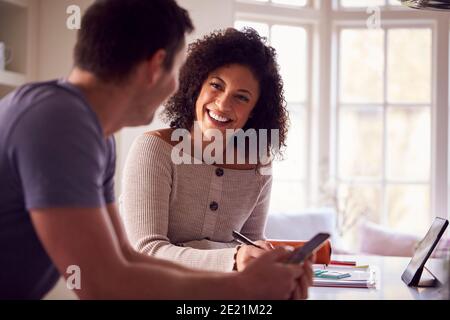 Couple With Digital Tablet Working From Home On Kitchen Counter Stock Photo