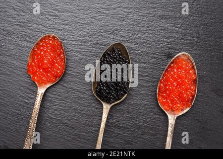 caviar of paddlefish fish and red chum salmon caviar in a spoon, black background, top view Stock Photo