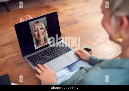 Woman With Laptop Having Video Chat With Friend Sitting On Floor At Home Relaxing Stock Photo