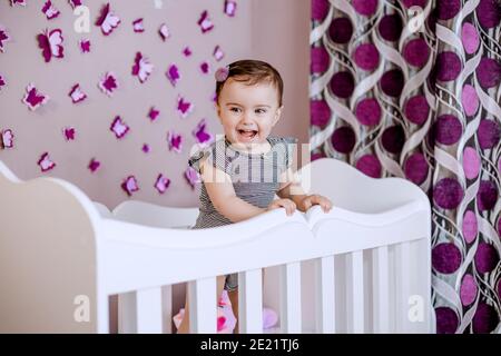 Cute, adorable baby enjoying her childhood in her crib. Nice deocrated bedroom with lots of butterflies Stock Photo
