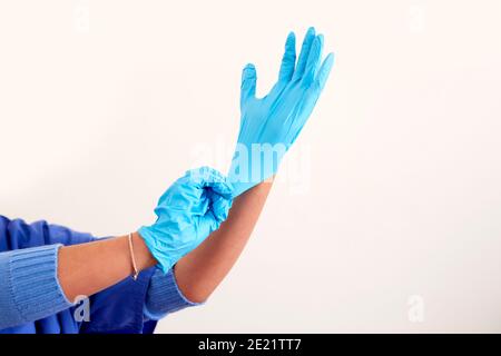 Close Up Of Female Nurse Wearing Scrubs Putting On Sterile PPE Gloves Stock Photo