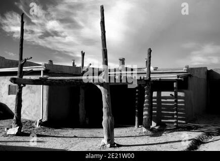 Grayscale shot of an old house under the sunlight and a cloudy sky in Taos Pueblo, New Mexico Stock Photo