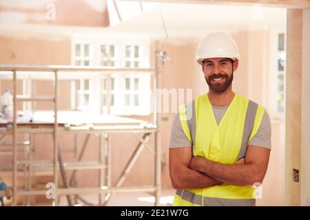 Portrait Of Smiling Male Builder Wearing Hard Hat Working In New Build Property Stock Photo